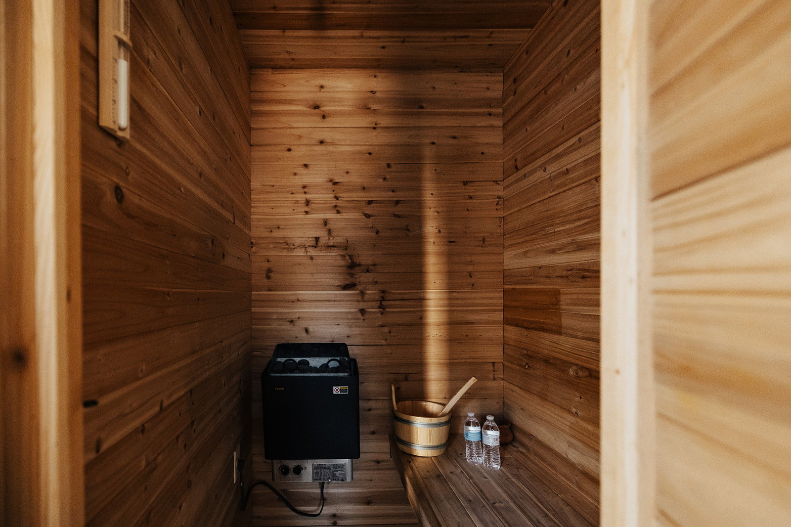 Dedicated sauna room featuring natural wood paneling, built-in wooden bench, and an integrated sauna heater