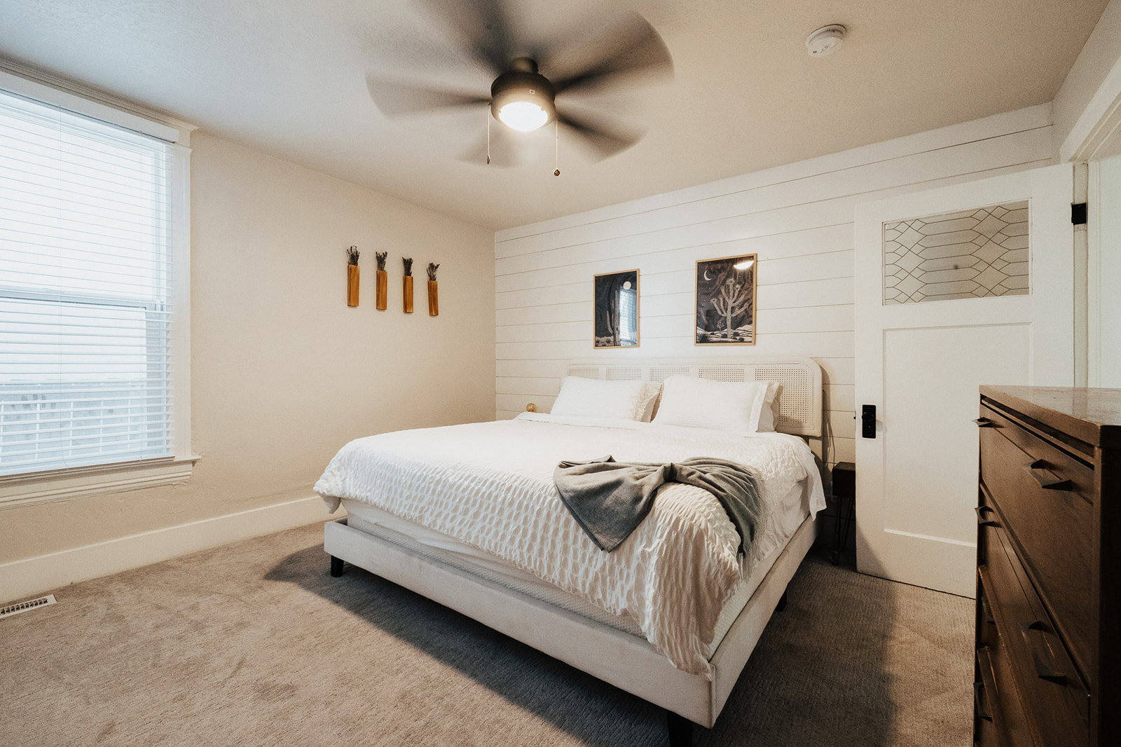 Primary Bedroom featuring an accent wall with horizontal white shiplap, a window with horizontal blinds, a ceiling fan with integrated lighting, and carpeted flooring