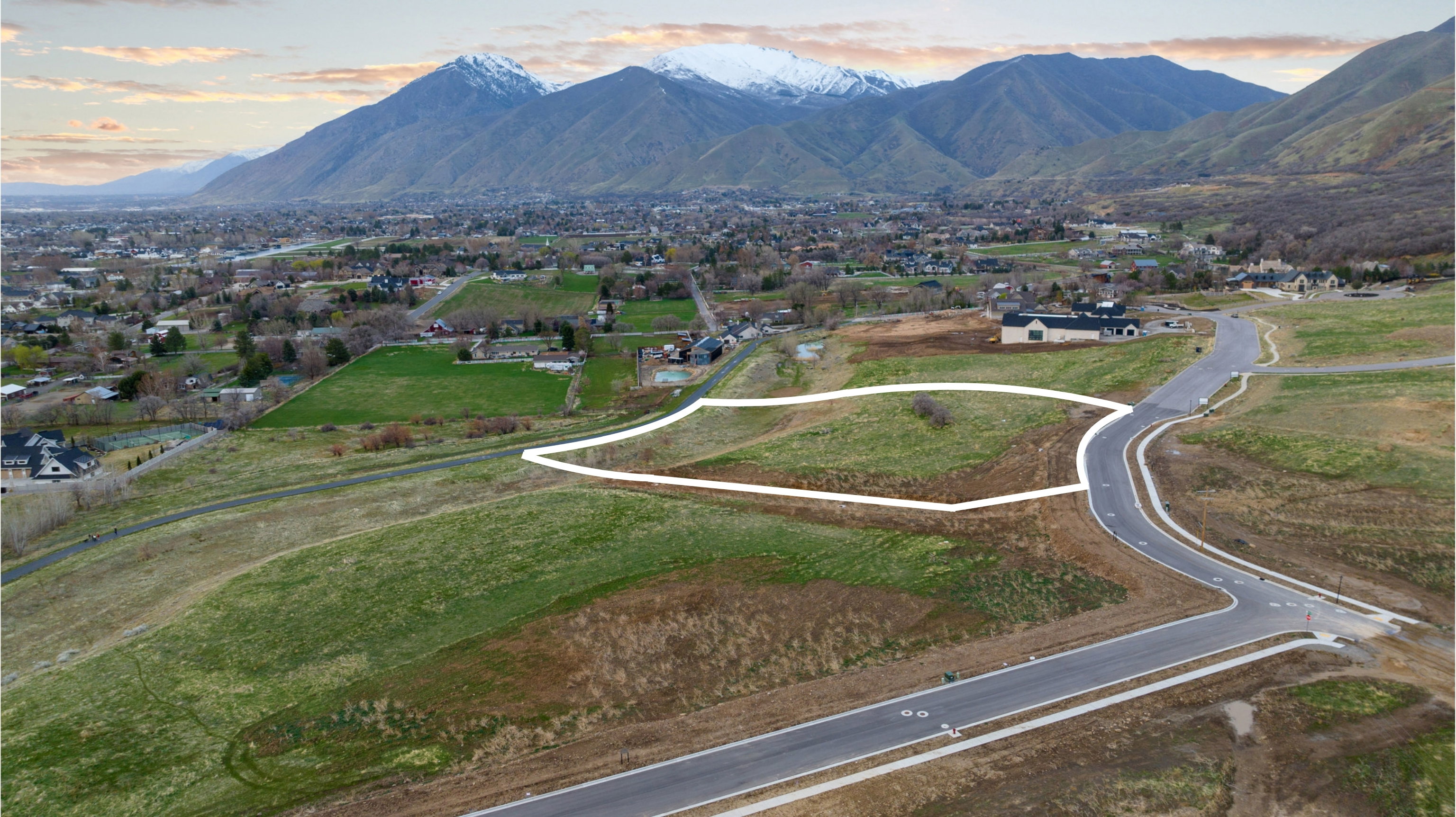 Expansive land parcel featuring a paved road frontage and surrounding natural terrain