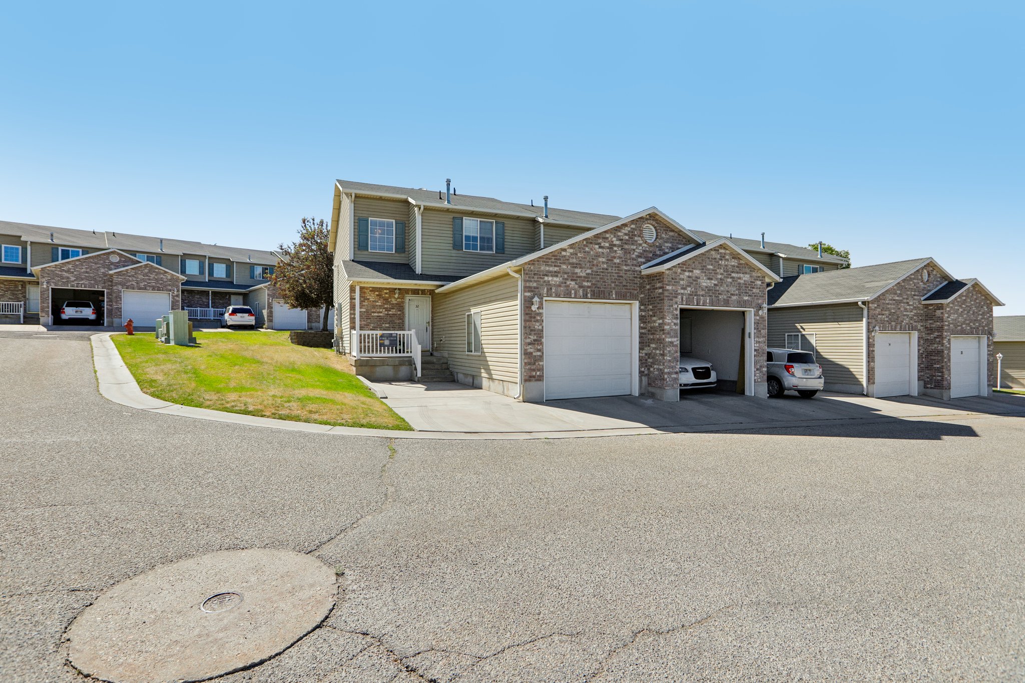 Townhome exterior featuring brick and siding accents, multiple garages, and a front porch entry