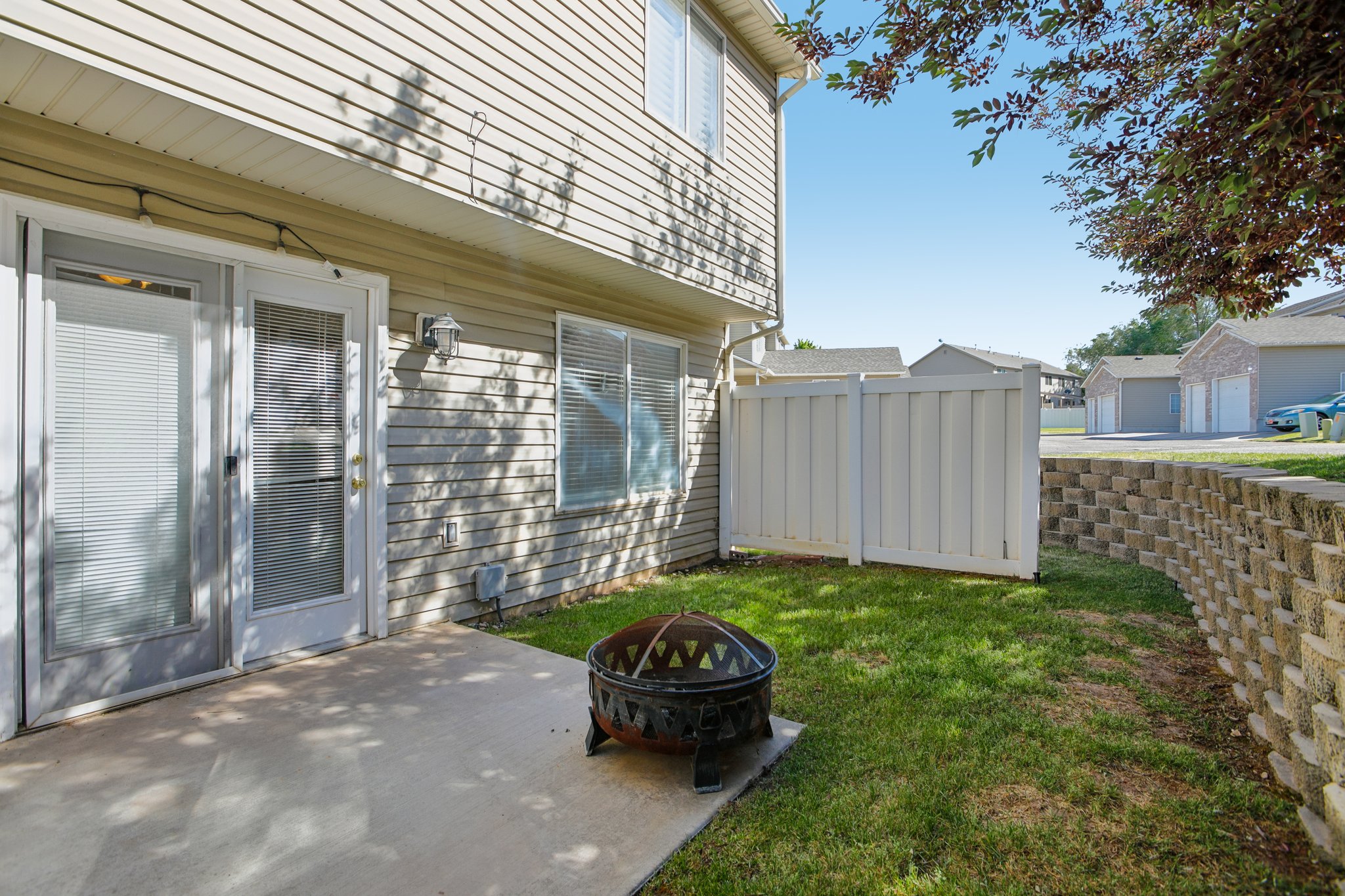 Private backyard patio with a concrete surface, bordered by a retaining wall and green lawn