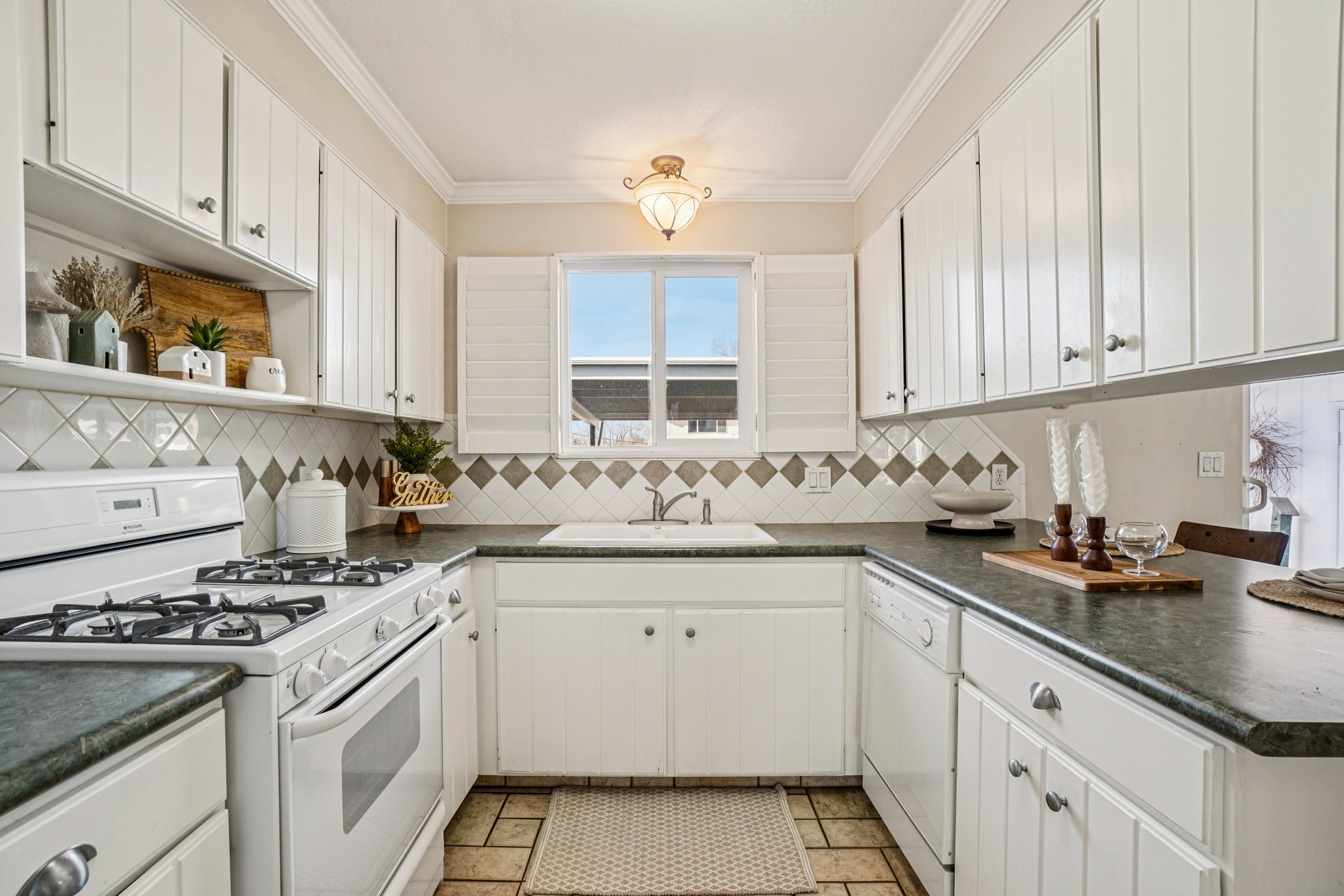 Kitchen featuring white cabinetry, dark countertops, a white gas range, and a white dishwasher