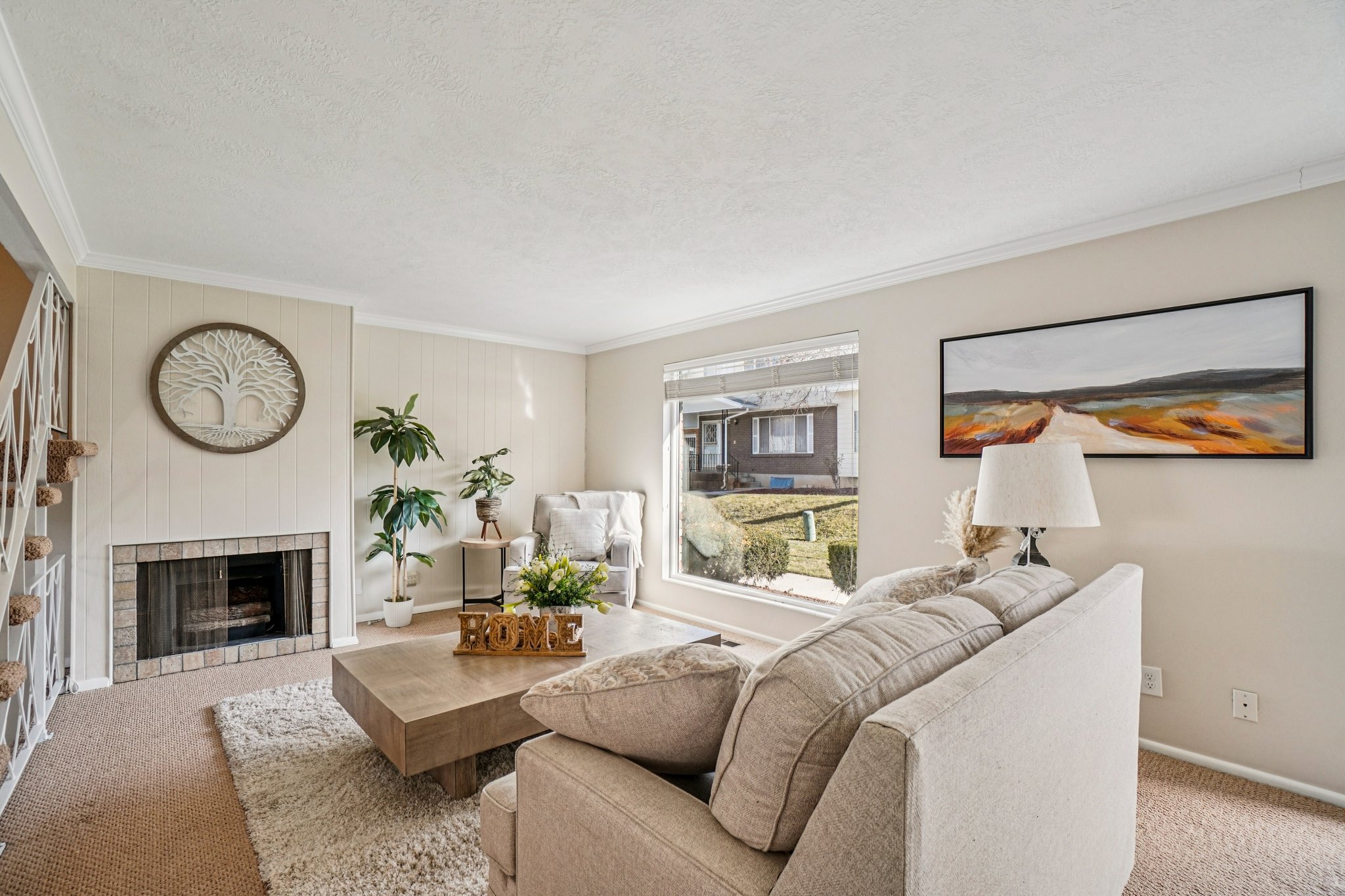 Living area featuring a large picture window, a fireplace with a stone surround, and light-toned wall paneling