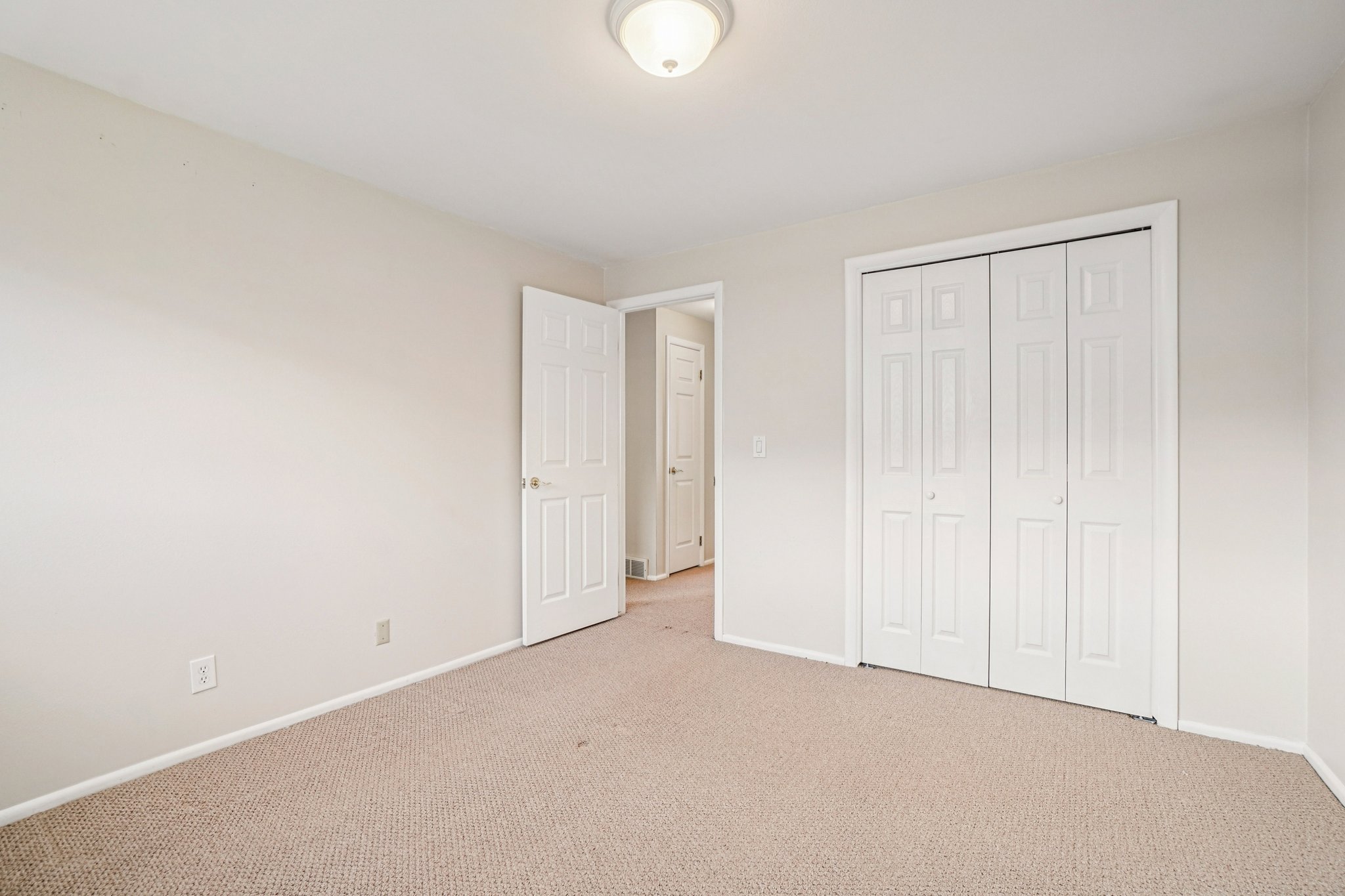 Neutral-toned walls and carpet flooring define this room, featuring a flush-mount ceiling light