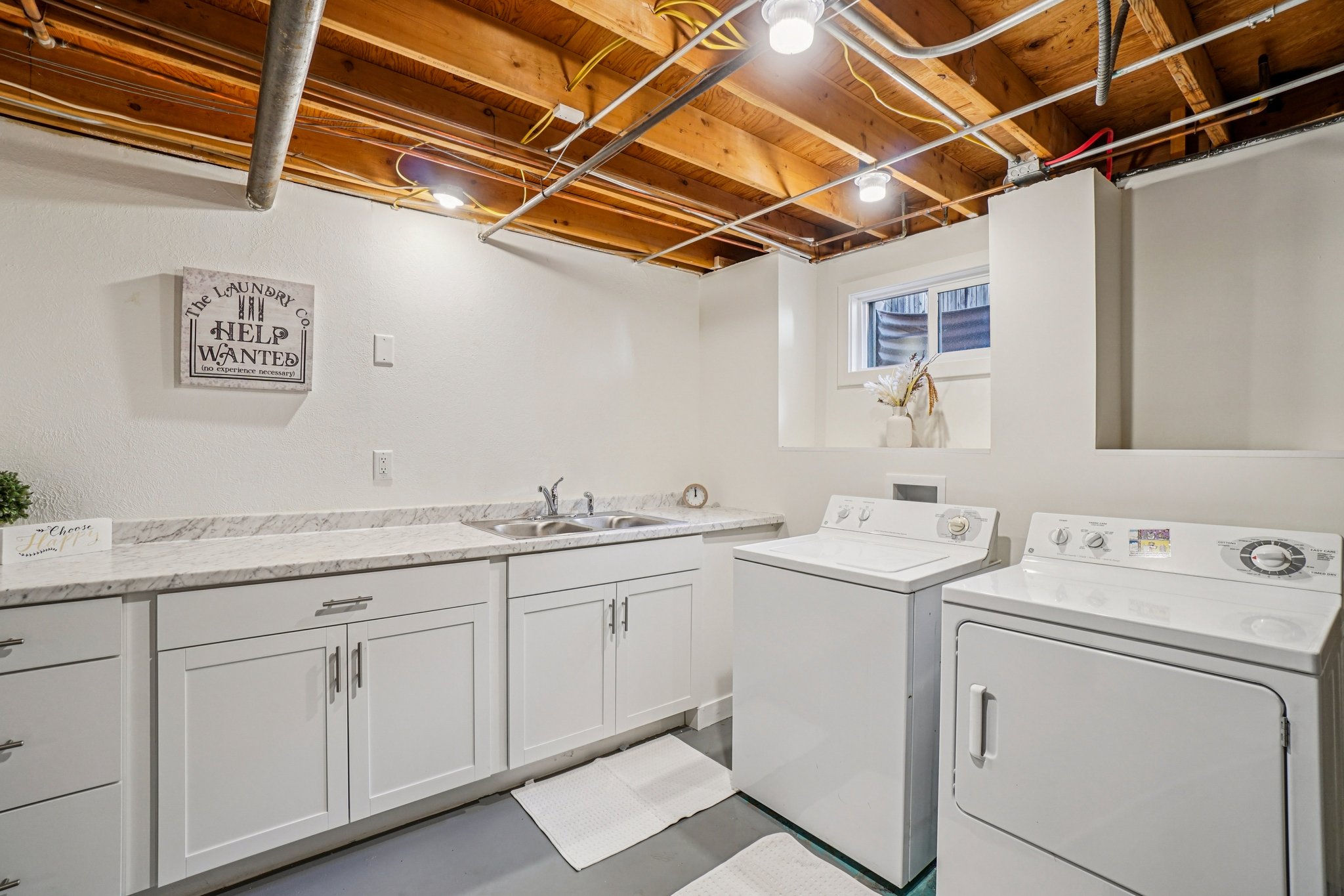 Dedicated laundry area featuring a utility sink, extensive white cabinetry, and light-toned countertops
