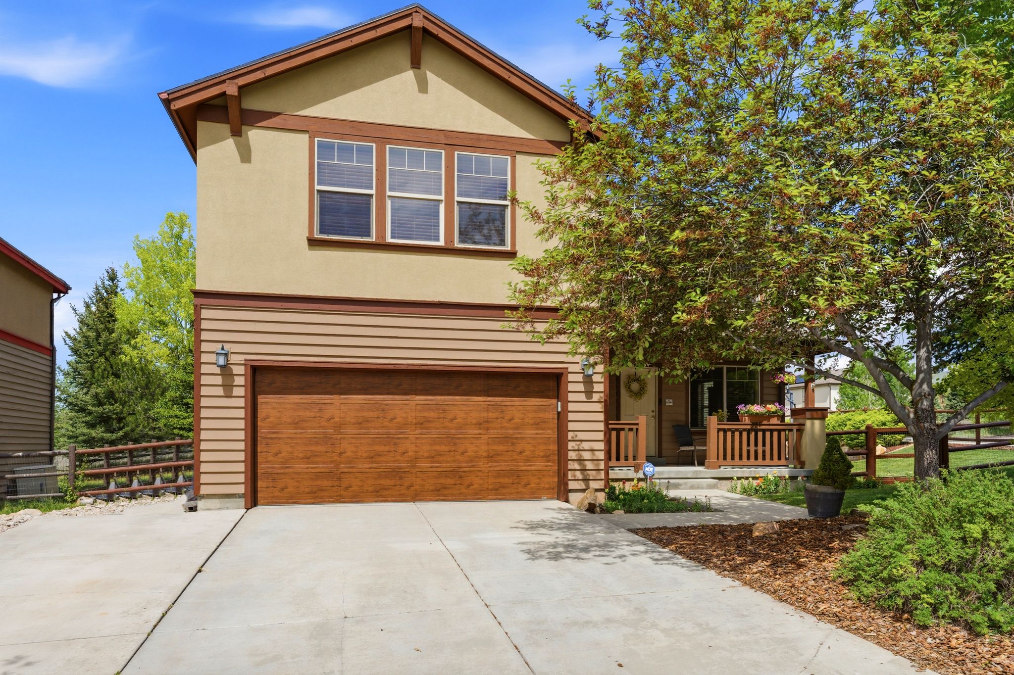 Exterior featuring a wood-finish garage door, stucco siding, and a covered front porch with wood railings