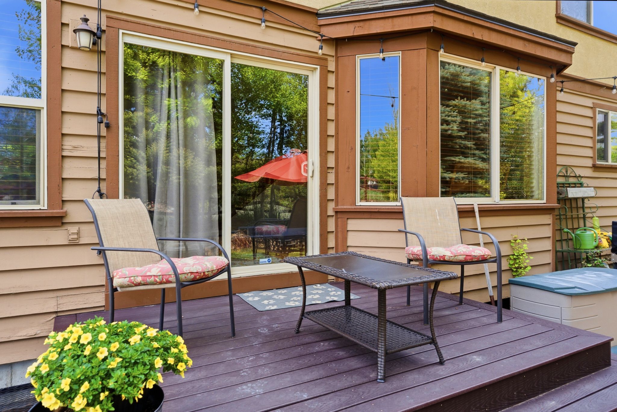 Wood-finish deck with a sliding glass door and multiple windows providing ample natural light