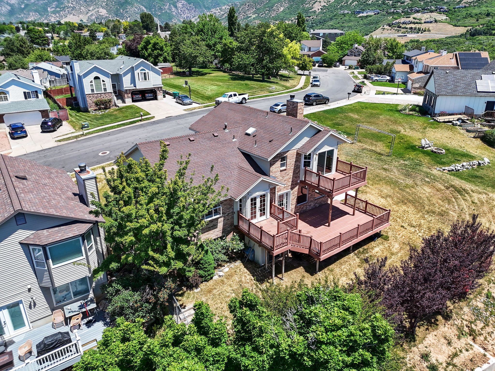 Multi-level residence featuring a brown shingle roof, stone veneer accents, and light-colored siding