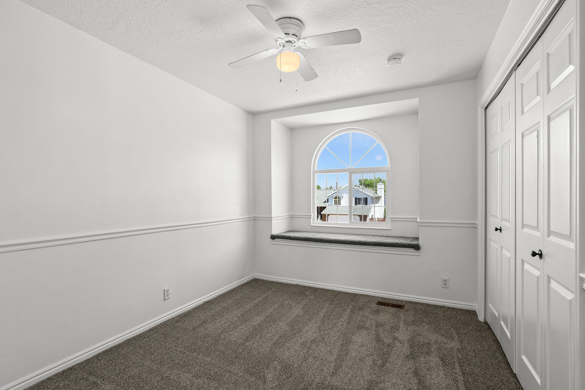 Room featuring an arched window, a built-in window bench, and an overhead ceiling fan with lighting