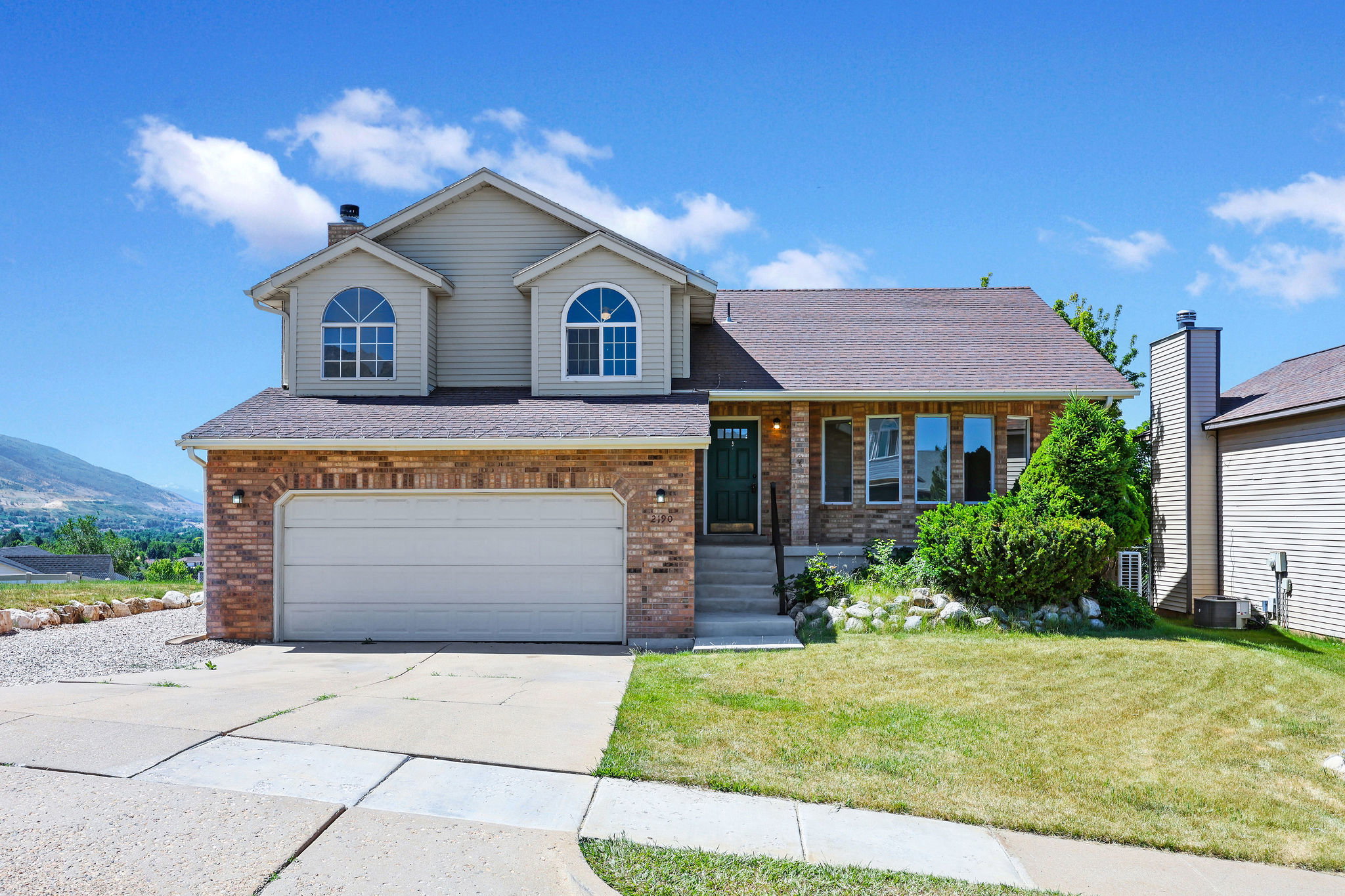 Two-story residence featuring brick and siding exterior, an attached two-car garage, and a covered front entry