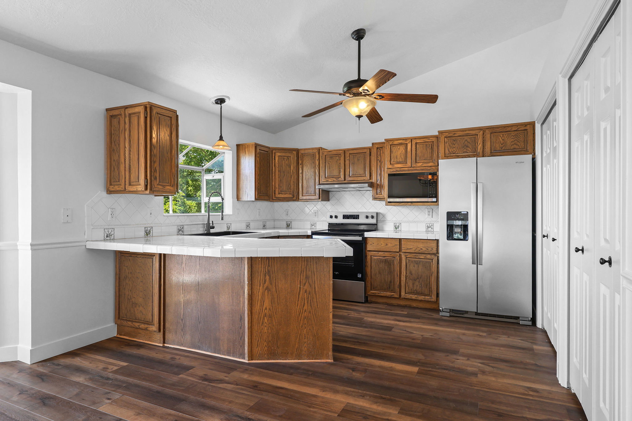 Kitchen featuring wood-finish cabinetry, stainless steel appliances, and a tiled breakfast bar