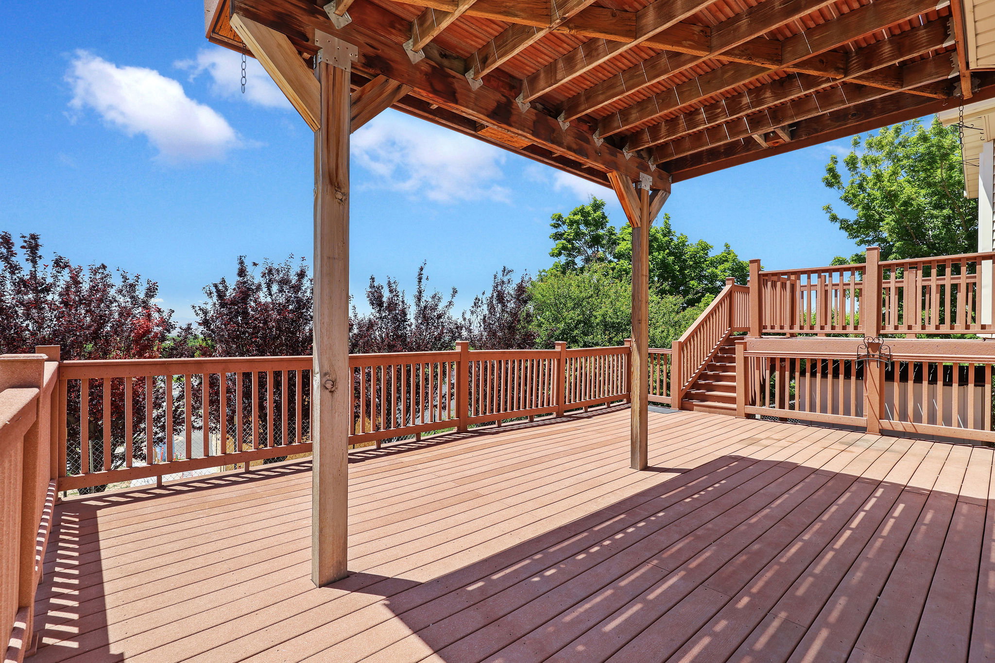 Multi-level wood deck featuring a covered area, wood railings, and stairs
