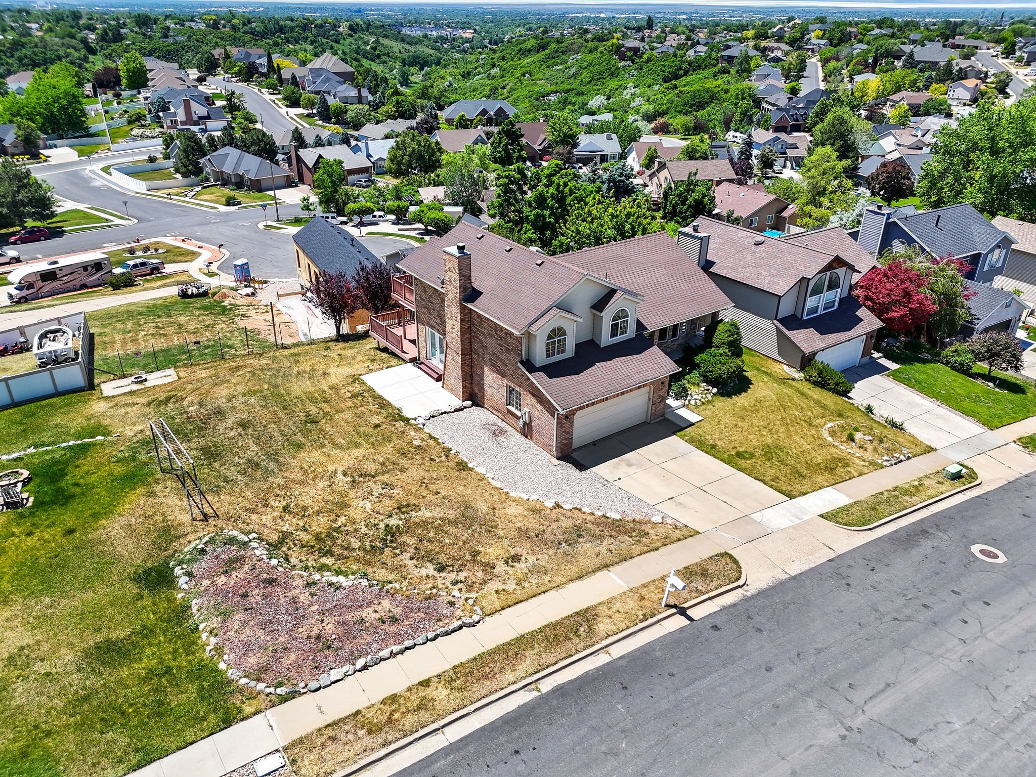 Brick exterior residence featuring an attached two-car garage, mature landscaping, and a substantial front yard