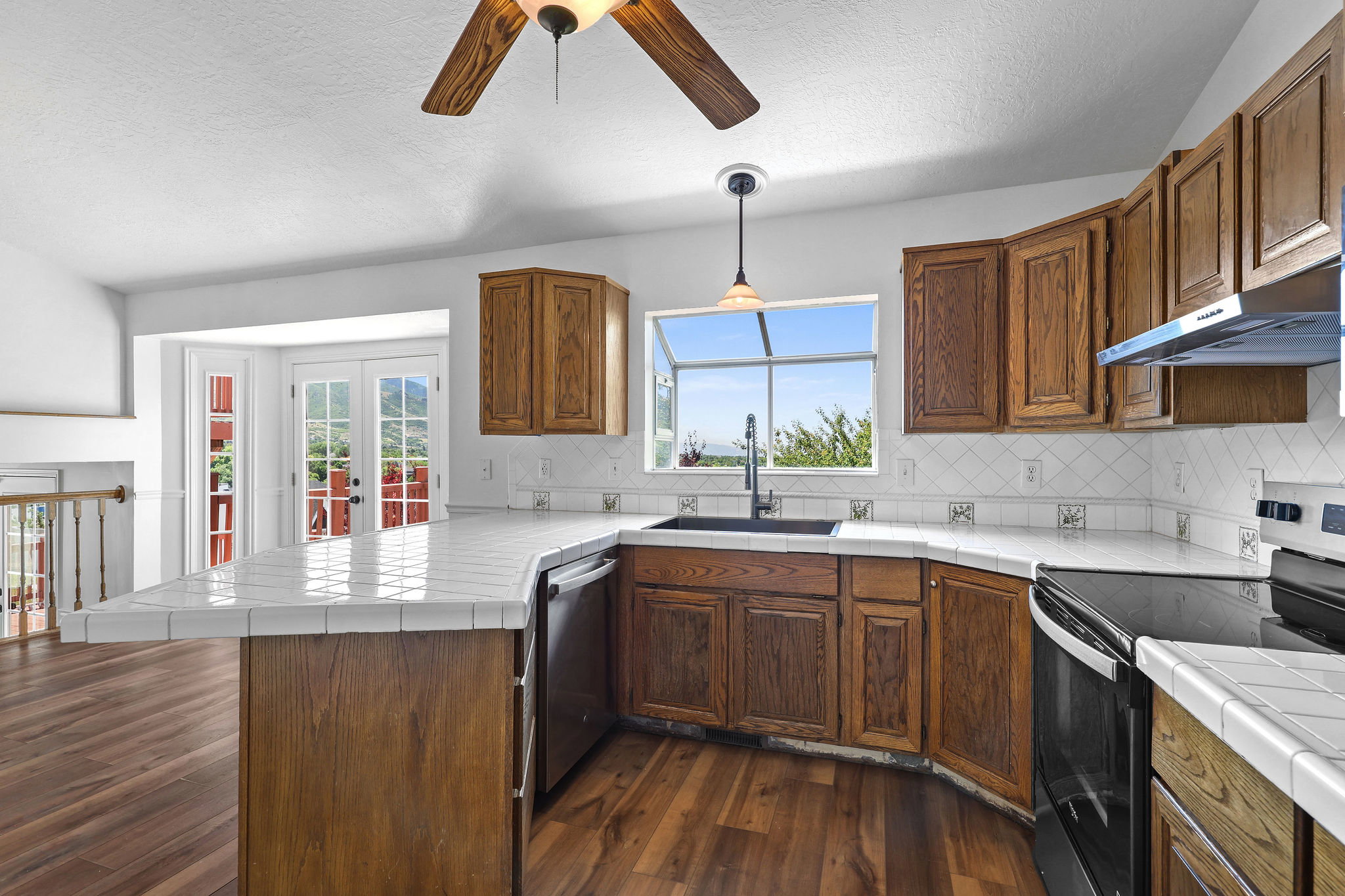 Kitchen featuring wood-finish flooring, wood cabinetry, tile countertops, and a tile backsplash