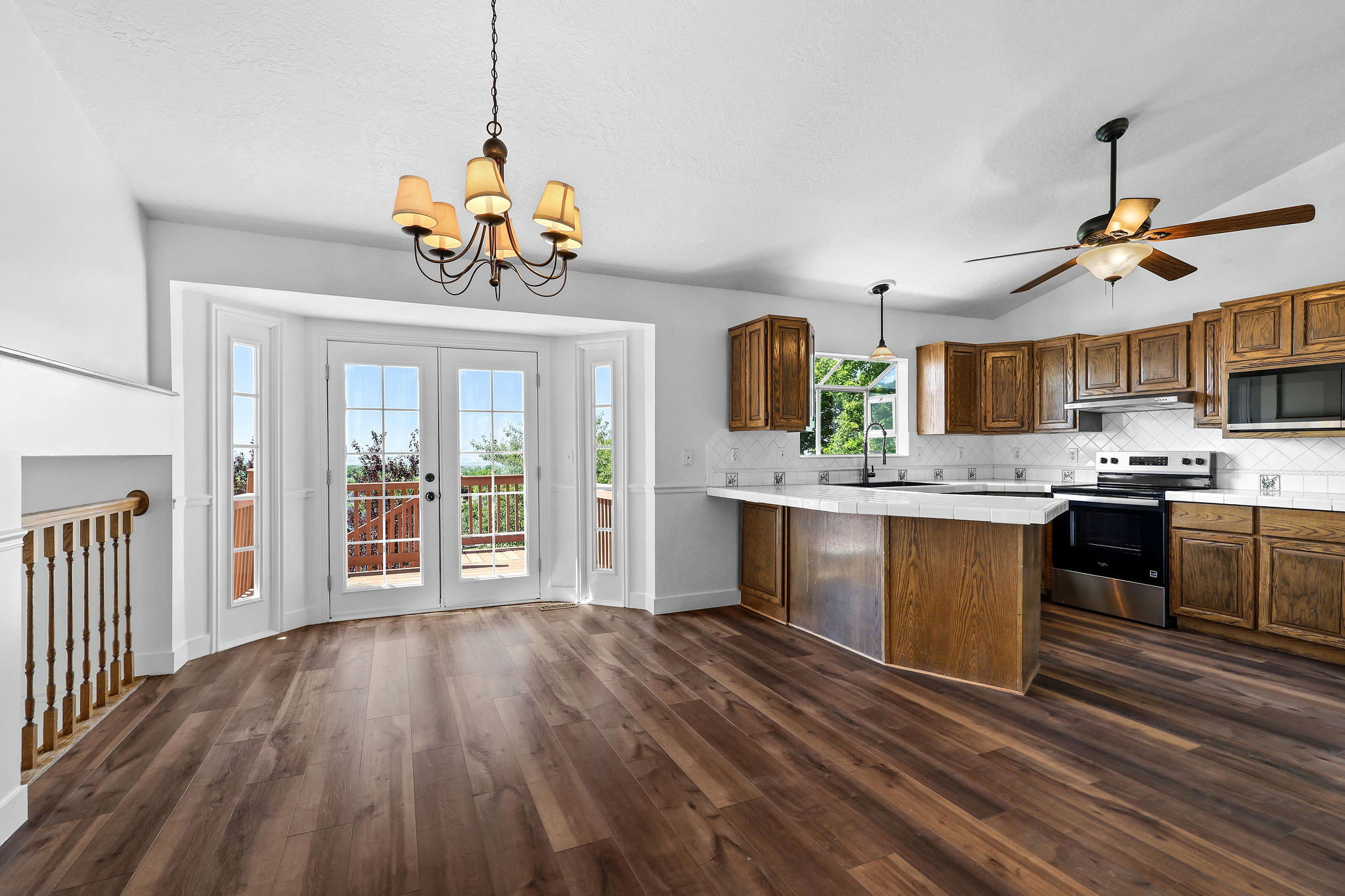 Wood-finish flooring throughout, complemented by a kitchen featuring wood cabinetry, stainless steel appliances, and a tiled backsplash