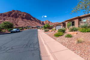 Desert landscape featuring a single-story residence with a stucco and stone facade, an attached garage, and a rock-mulched front yard with mature desert plantings