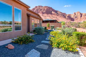 Landscaped exterior featuring a stucco facade, large windows, dark gravel, stepping stones, and mature desert plantings