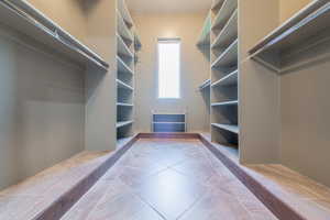 Spacious walk-in closet featuring extensive built-in shelving, hanging rods, and a central tiled floor