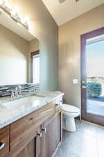 Bathroom vanity featuring a rectangular undermount sink, stone countertop, and tile backsplash