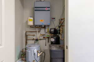 Water heater system featuring a tankless unit, a traditional tank unit, a water softener, and visible copper plumbing
