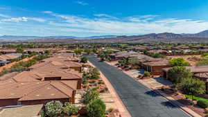 Residential neighborhood featuring a paved street, terracotta-tiled roofs, and surrounding mountainous terrain