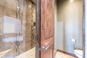 Glass-enclosed shower featuring large format wall tiles, decorative mosaic tile accents, and a pebble stone floor
