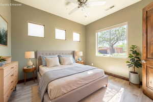 Bedroom featuring light wood-finish flooring, a ceiling fan, a large window, and three high square windows