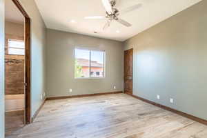Spacious room featuring wood-finish flooring, a ceiling fan, recessed lighting, and a window providing natural light