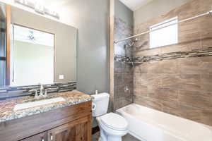 Bathroom featuring a wood-finish vanity with an undermount sink and stone-look countertop