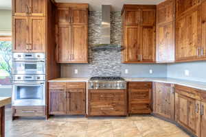 Gourmet kitchen with custom wood cabinetry, stainless steel double ovens, a six-burner gas range, and a mosaic tile backsplash