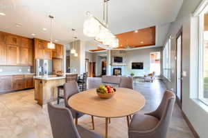 Open-concept kitchen and dining area featuring a wood-finish island with seating, stainless steel appliances, and extensive wood cabinetry