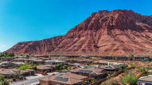 Residential community nestled at the base of a prominent red rock formation, featuring contemporary residences with varying rooflines