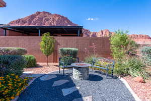 Landscaped outdoor area featuring a stone fire pit, decorative benches, and a privacy wall