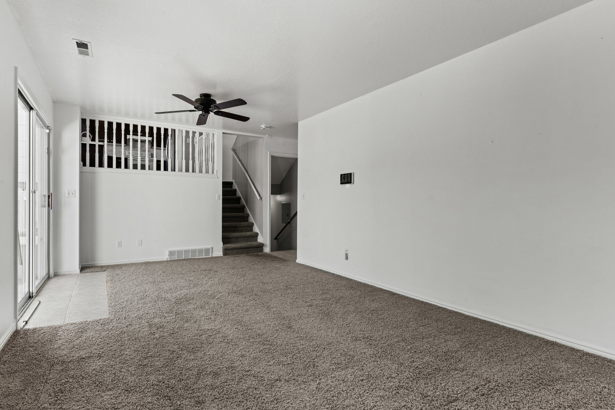 Spacious living area featuring neutral carpeting and white wall finishes