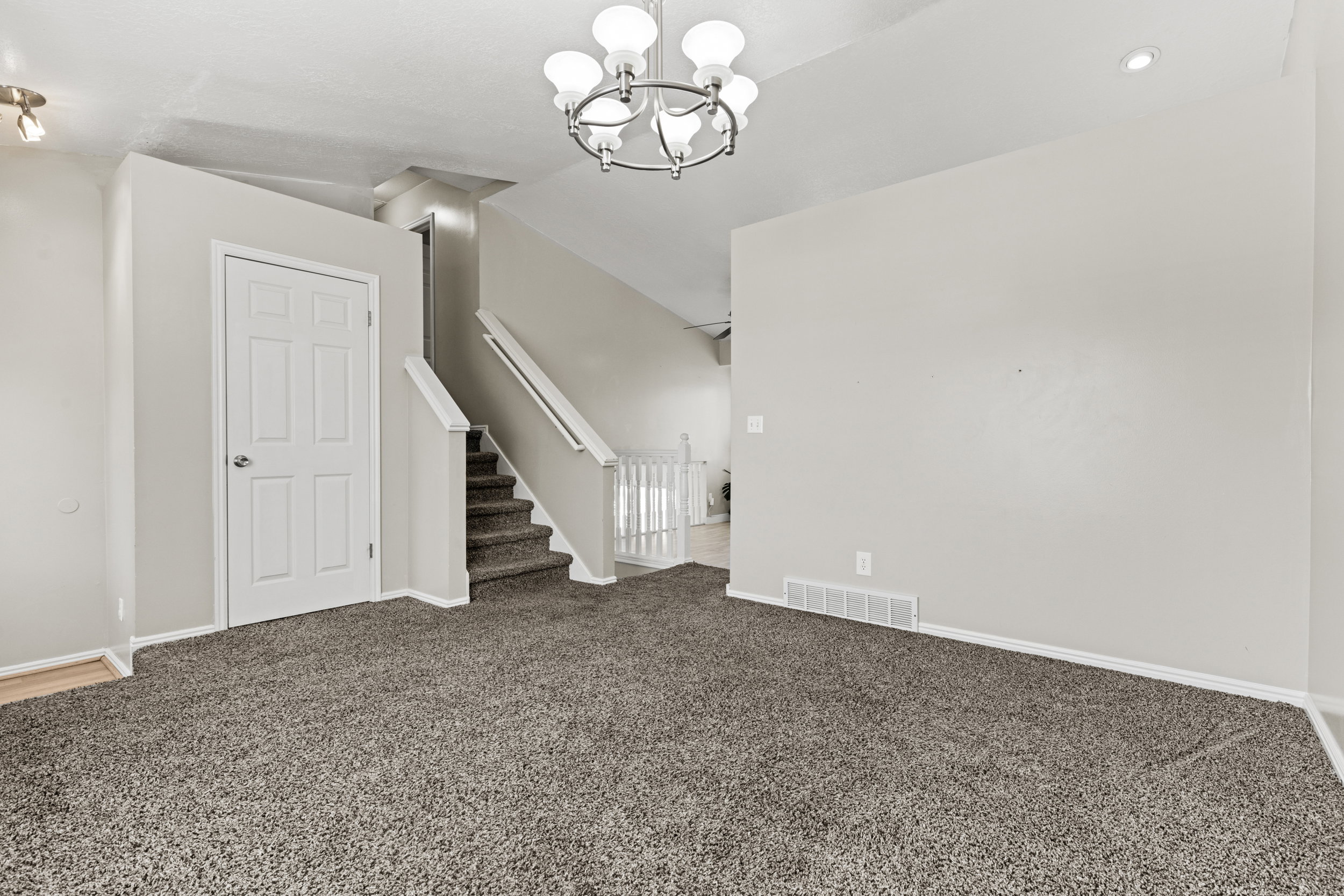 Spacious room with plush carpeting, neutral wall finishes, and a contemporary five-light chandelier