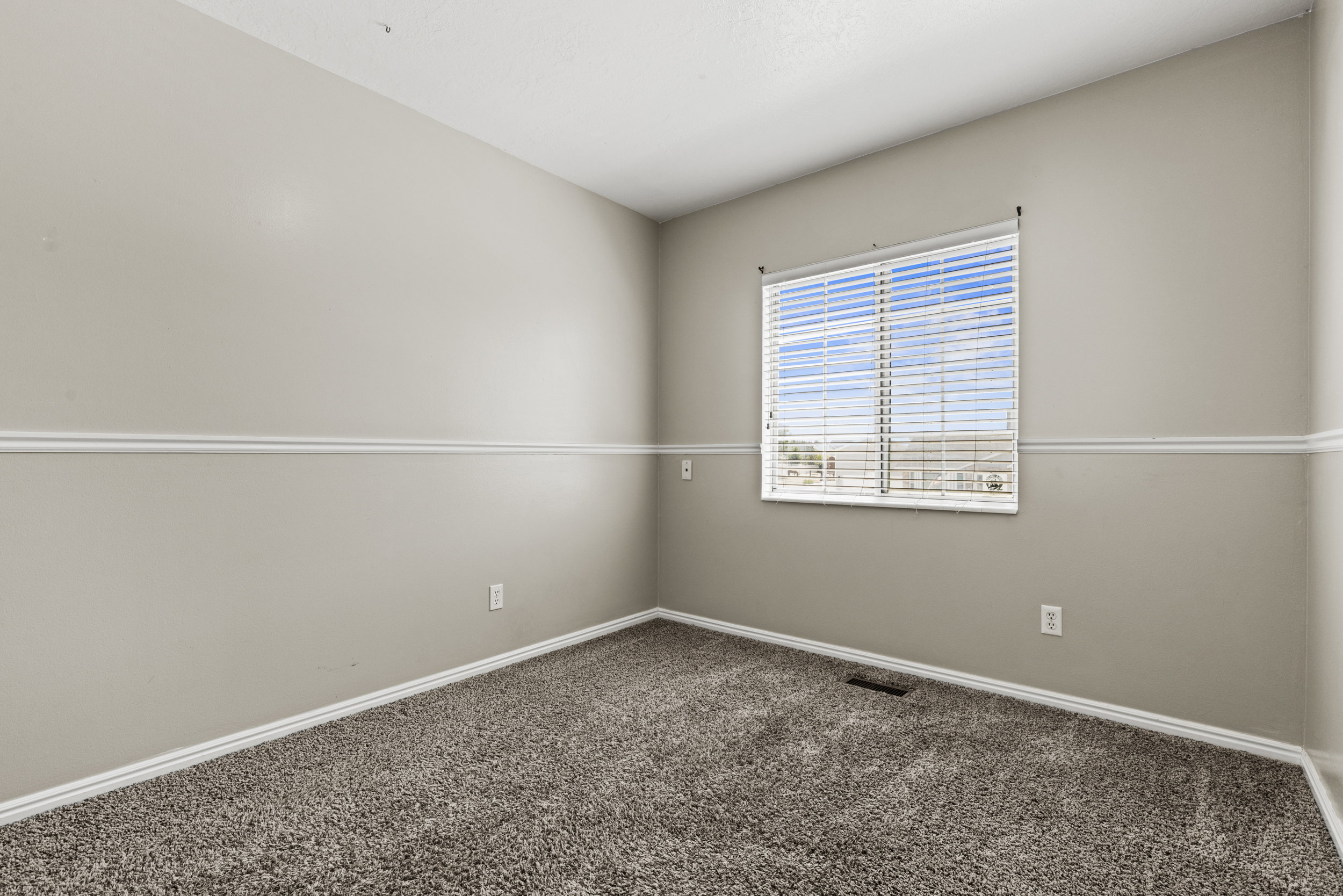 Carpeted room with a single window featuring horizontal blinds