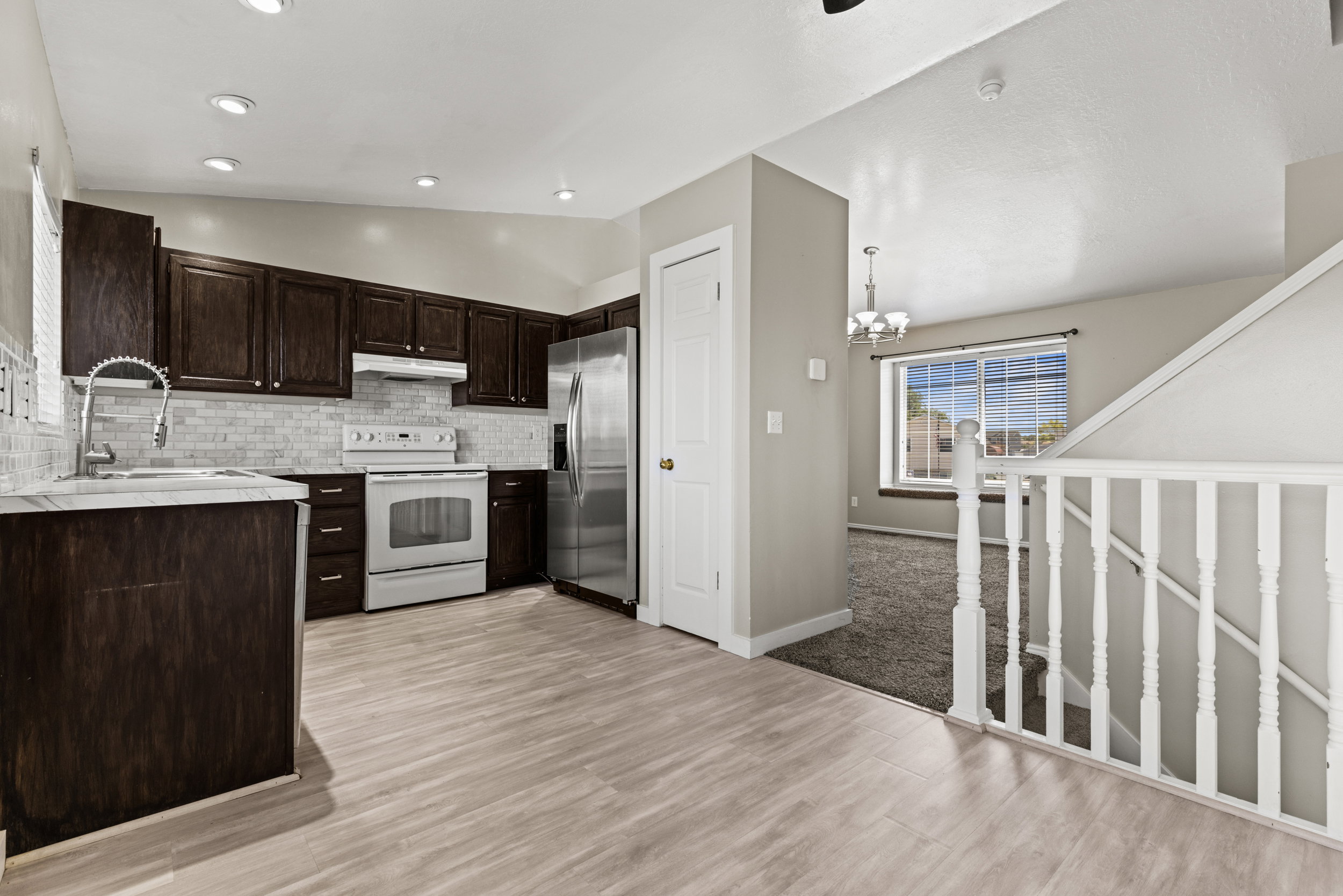 Kitchen featuring dark wood cabinetry, stainless steel refrigerator, white range, and a subway tile backsplash