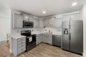 Modern kitchen featuring light gray cabinetry with dark hardware, white countertops, and wood-finish flooring