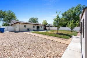 Spacious backyard featuring a large gravel area, a green lawn, and mature trees