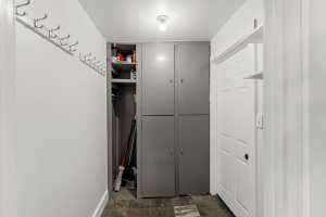 Hallway featuring wall-mounted coat hooks, an integrated open storage area, and gray cabinetry