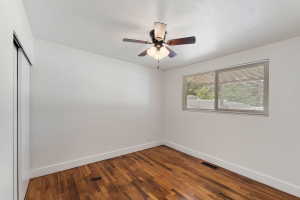 Room featuring wood-finish flooring, white walls, and a ceiling fan with integrated lighting