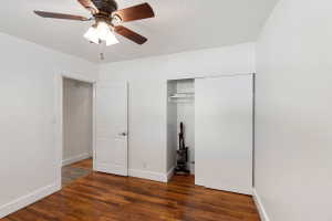 Room featuring rich wood-finish flooring, white painted walls, and a ceiling fan with integrated lighting