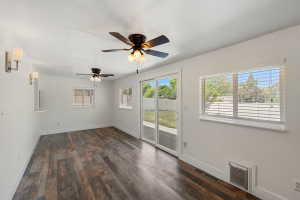 Spacious room featuring wood-finish flooring, white walls, and multiple ceiling fans