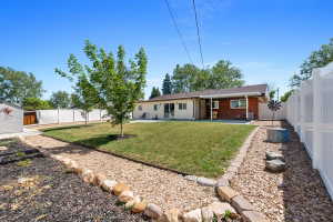Expansive backyard featuring a manicured lawn, established trees, and a gravel pathway bordered by natural stones