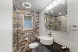 Bathroom featuring a vessel sink, dark countertop, and gray vanity with cabinet storage