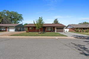 Ranch-style residence featuring a brick facade, single-car garage, and a brown shingle roof
