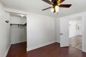 Room featuring wood-finish flooring, a ceiling fan with integrated lighting, and white walls