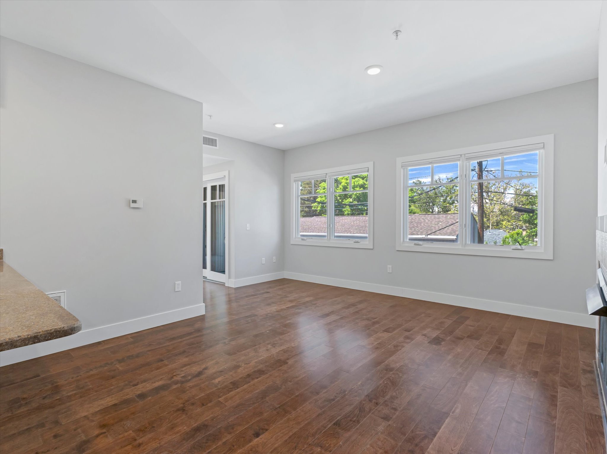 Spacious room featuring wood-finish flooring, light grey wall paint, and multiple windows with white trim