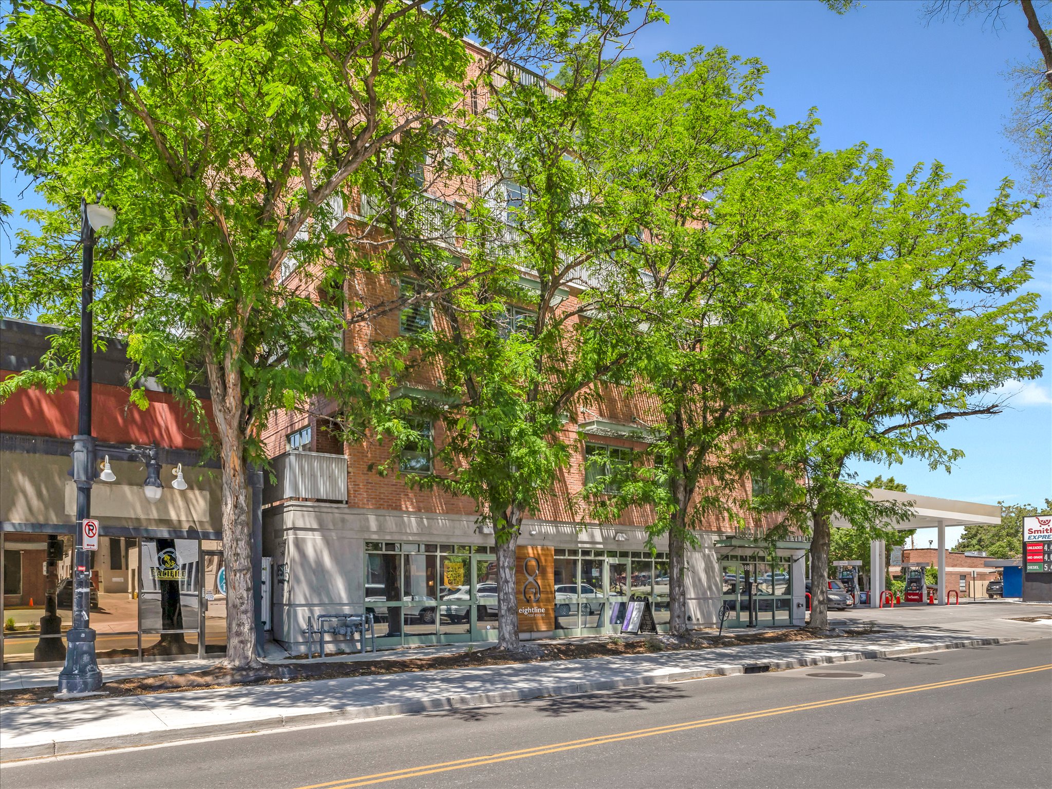 Multi-story brick building featuring ground-floor retail storefronts with large glass windows