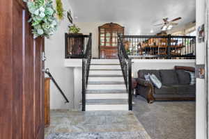 Entryway featuring stone-finish flooring, a rich wood-panel door, and a staircase with decorative iron railings